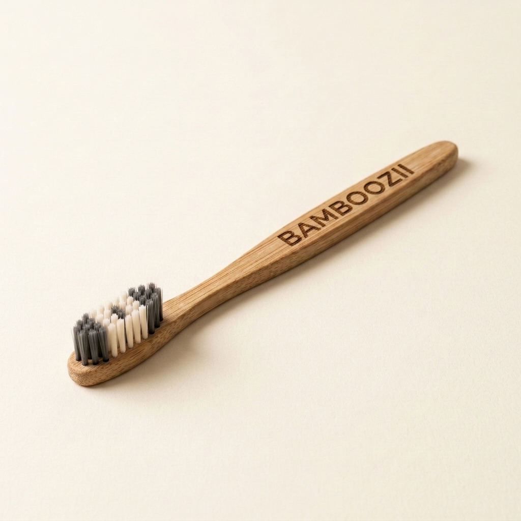 Single Bamboozii bamboo toothbrush with charcoal soft bristles on a cream background
